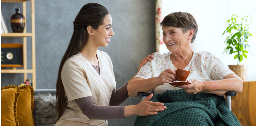 Nurse serving coffee to elderly woman